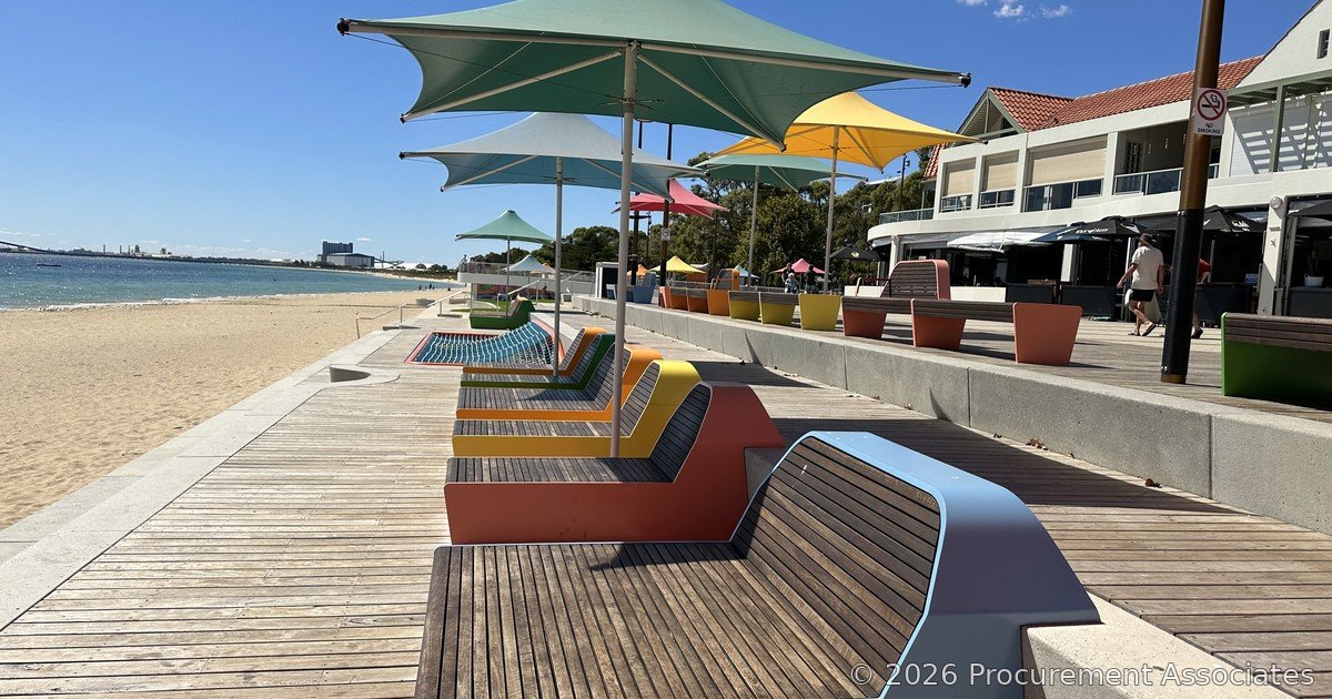Waterfront boardwalk and beach with shade sails along a coastal foreshore