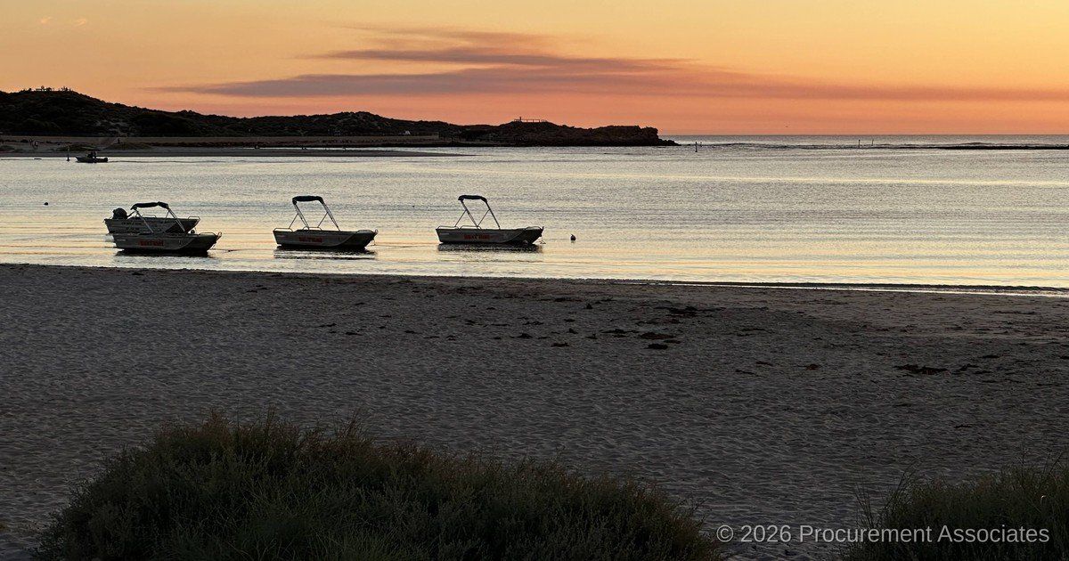 Golden-hour sunset over a calm coastal foreshore with moored boats